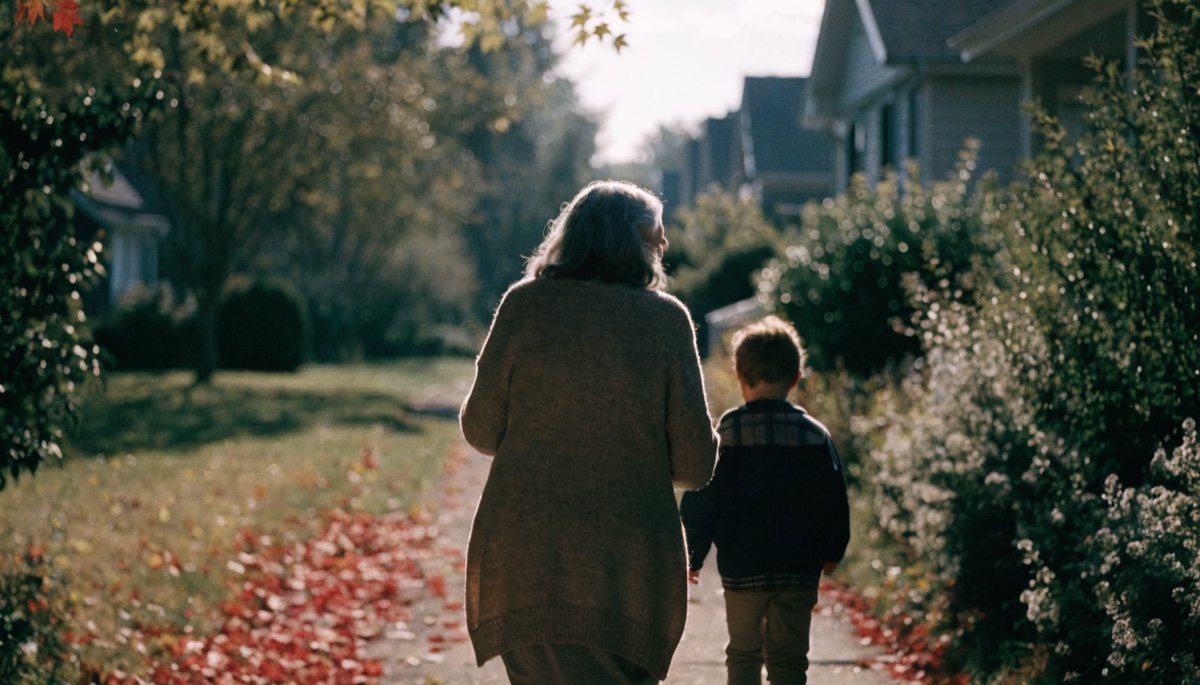 An elderly woman and a child walking along an autumn footpath, seen from behind
