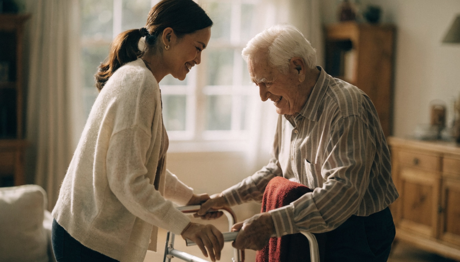 A caregiver helping an elderly man in a bright Canadian living room