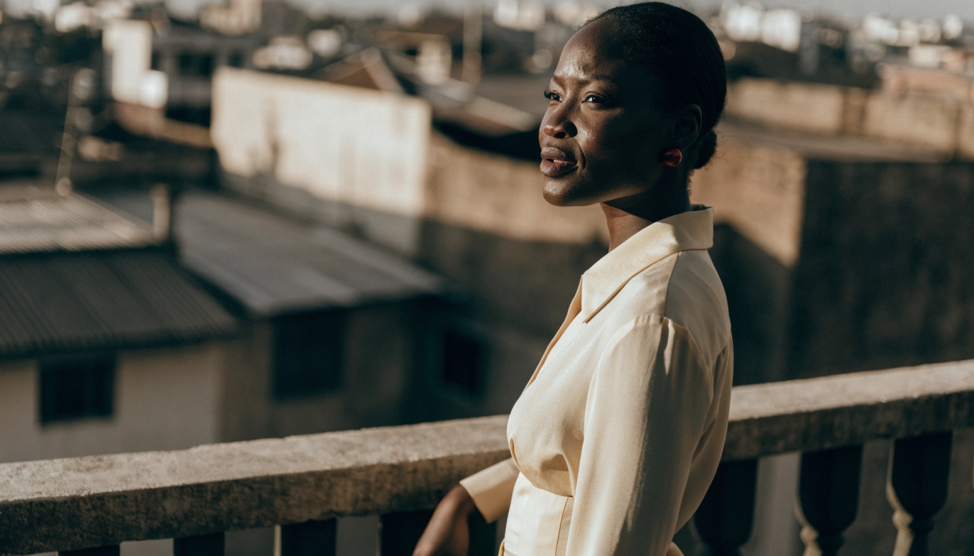 A confident Ghanaian woman on a sunlit balcony in Accra