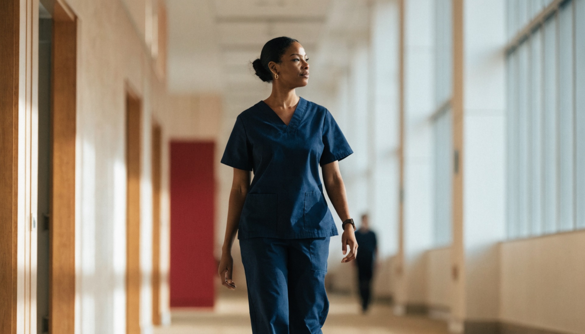 A nurse walking through a modern Canadian hospital corridor