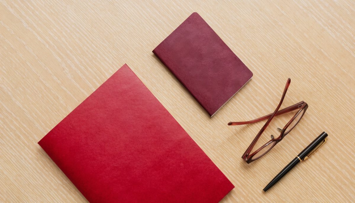 A red document folder and a passport on a desk